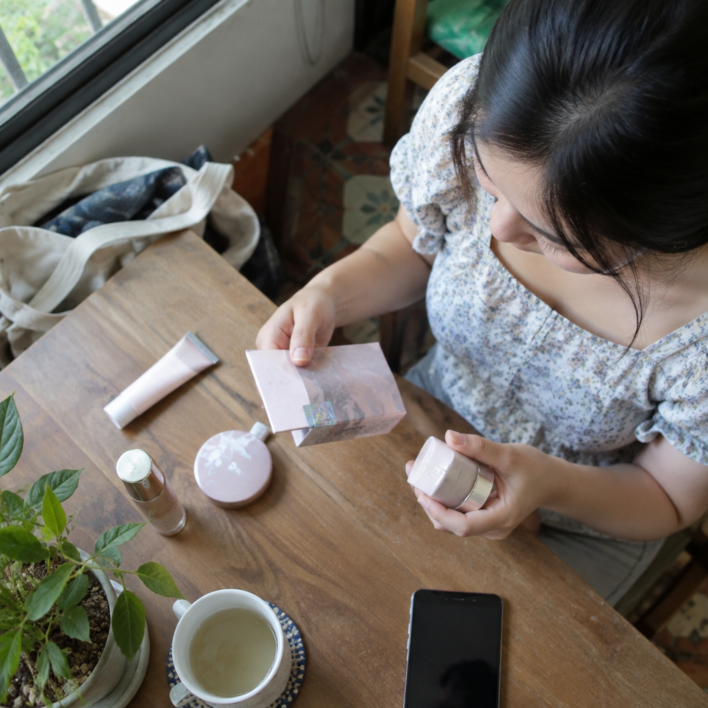 Một người phụ nữ đang cẩn thận kiểm tra bao bì sản phẩm mỹ phẩm, đây là một bước quan trọng trong việc kiểm định mỹ phẩm chính hãng